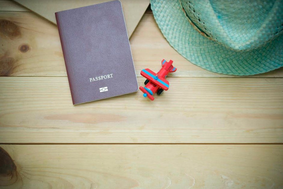 Photo d'un passeport, d'un jouet et d'un chapeau sur une table
